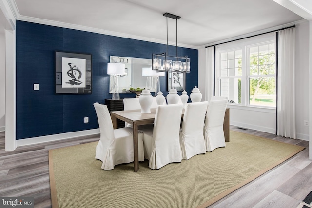 dining space with ornamental molding, an inviting chandelier, and hardwood / wood-style floors