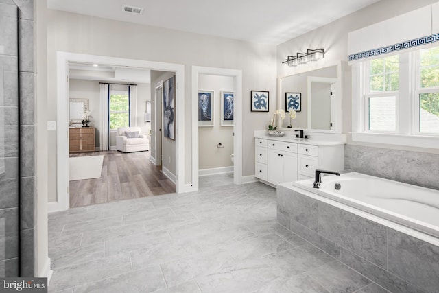 bathroom featuring vanity, hardwood / wood-style floors, toilet, and tiled bath