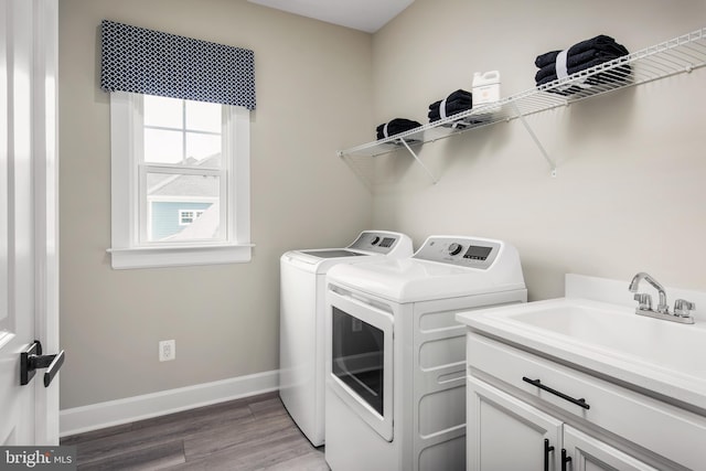 laundry area with sink, cabinets, separate washer and dryer, and hardwood / wood-style floors