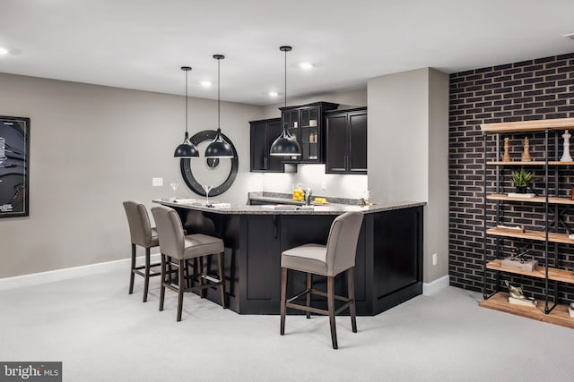 bar featuring hanging light fixtures, light stone counters, light colored carpet, and brick wall