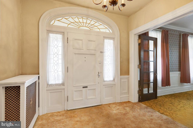 entrance foyer featuring a chandelier, carpet, and a wealth of natural light