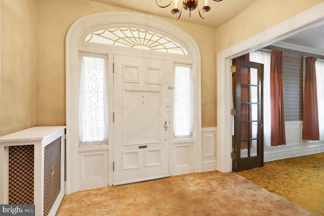 foyer entrance with ornamental molding, carpet floors, and a wealth of natural light