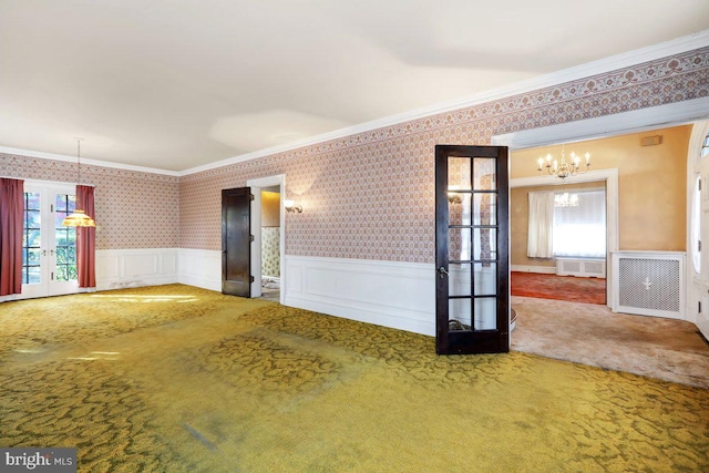 empty room with ornamental molding, french doors, a notable chandelier, and carpet floors