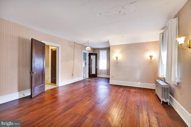 spare room with dark wood-type flooring and radiator