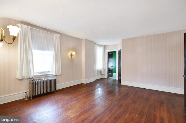 spare room with dark wood-type flooring and radiator