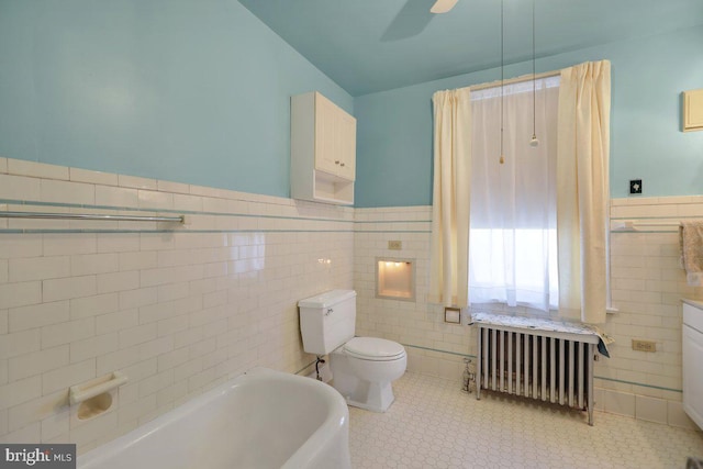 bathroom with a tub to relax in, toilet, tile walls, radiator heating unit, and ceiling fan