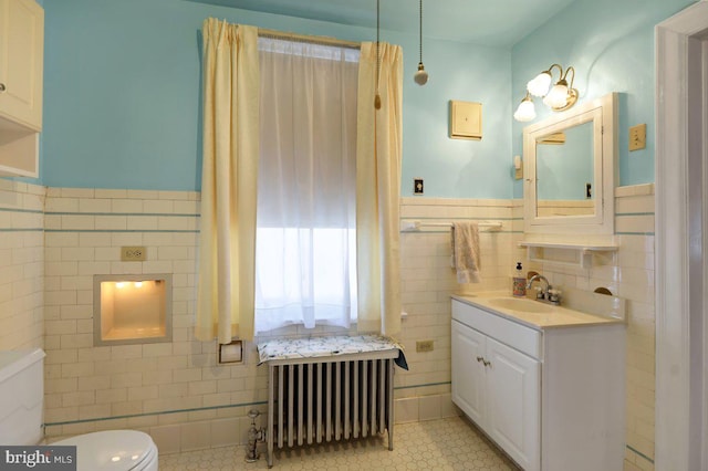 bathroom featuring radiator, toilet, tile walls, and vanity