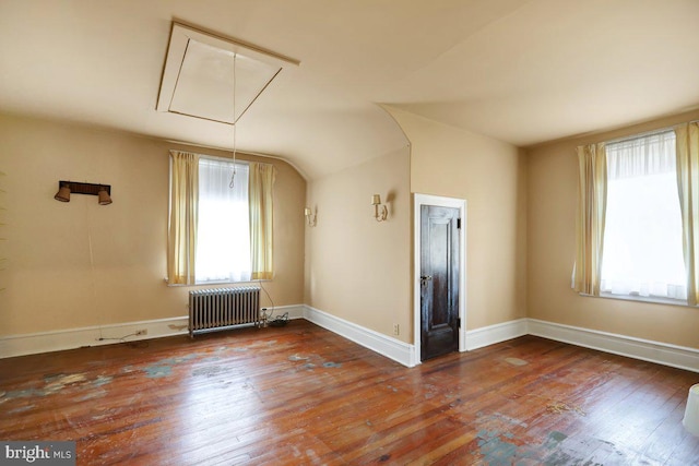 spare room featuring wood-type flooring, radiator heating unit, and plenty of natural light