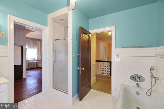 bathroom with vanity, independent shower and bath, radiator heating unit, and hardwood / wood-style floors