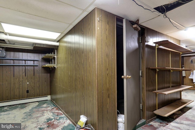 basement featuring baseboard heating and wooden walls