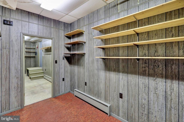 washroom with baseboard heating, wooden walls, and dark carpet