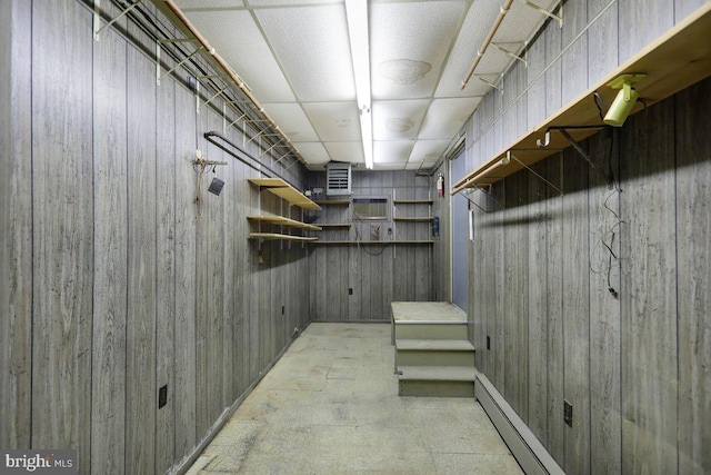 basement featuring wooden walls and a baseboard radiator