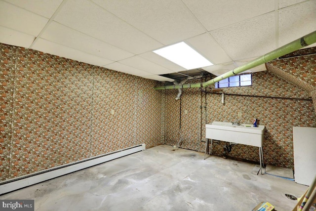 basement featuring a drop ceiling and a baseboard radiator