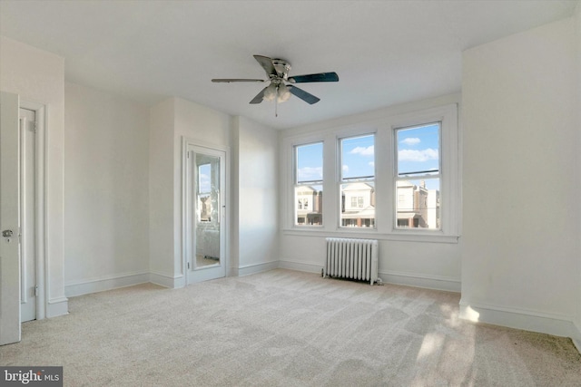 carpeted spare room featuring radiator heating unit and ceiling fan