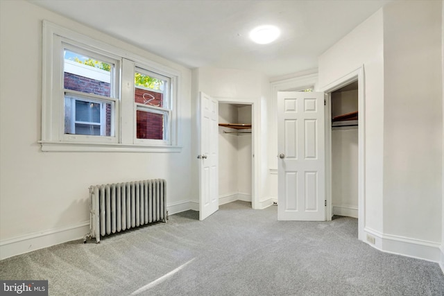 unfurnished bedroom with light colored carpet and radiator heating unit