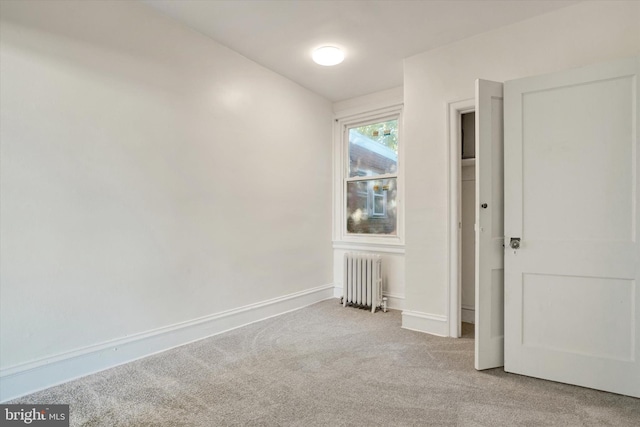 carpeted spare room featuring radiator heating unit