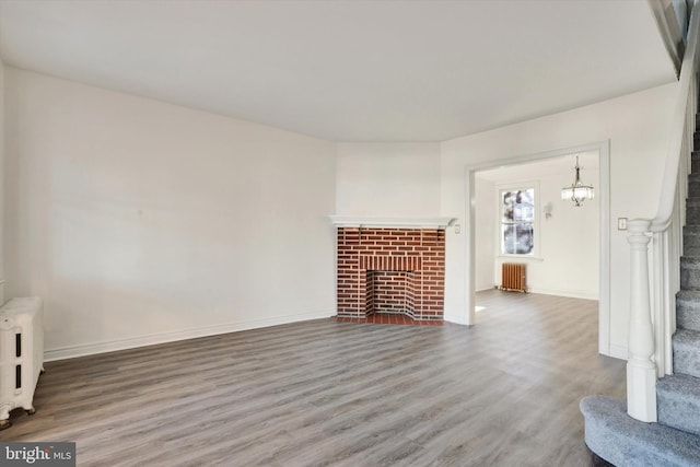 unfurnished living room featuring a fireplace, wood-type flooring, and radiator heating unit