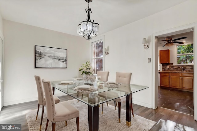 dining area with ceiling fan with notable chandelier and dark hardwood / wood-style flooring