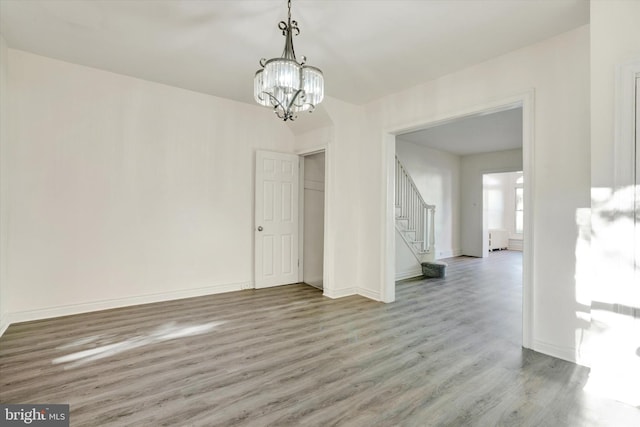 unfurnished dining area featuring wood-type flooring and a notable chandelier