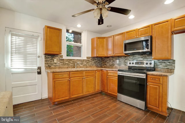 kitchen featuring stainless steel appliances, dark wood-type flooring, sink, ceiling fan, and backsplash