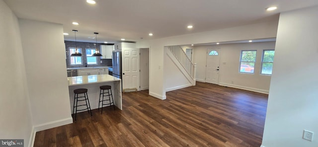 kitchen with backsplash, hanging light fixtures, white cabinetry, a breakfast bar area, and dark hardwood / wood-style floors