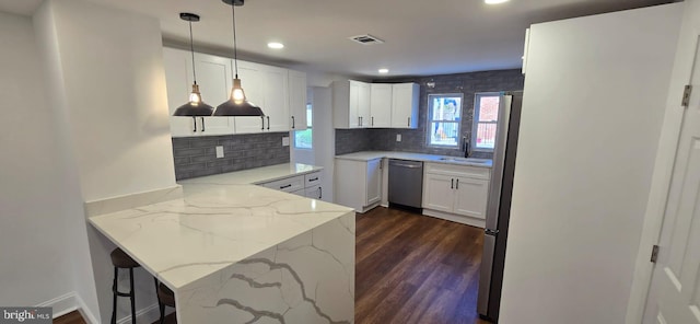 kitchen with kitchen peninsula, light stone counters, dark hardwood / wood-style flooring, white cabinetry, and decorative light fixtures