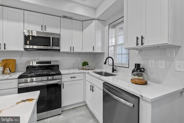 kitchen featuring white cabinetry, backsplash, appliances with stainless steel finishes, and sink