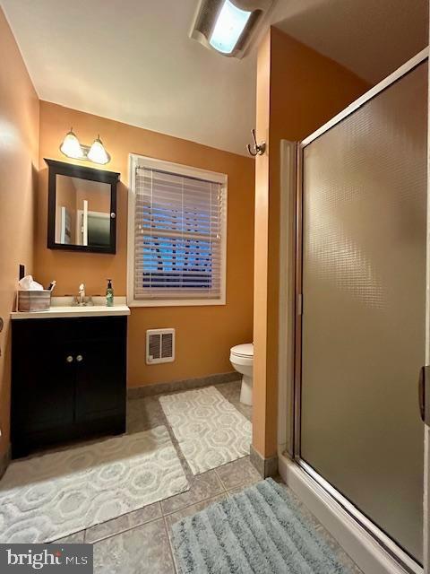 bathroom featuring vanity, toilet, tile patterned floors, and an enclosed shower