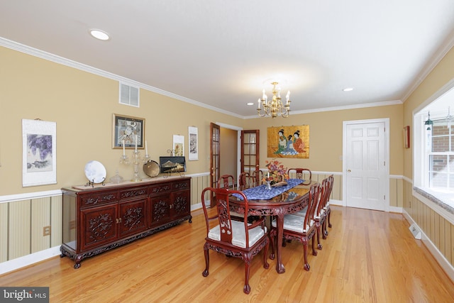 dining room featuring a notable chandelier, ornamental molding, and light wood-type flooring