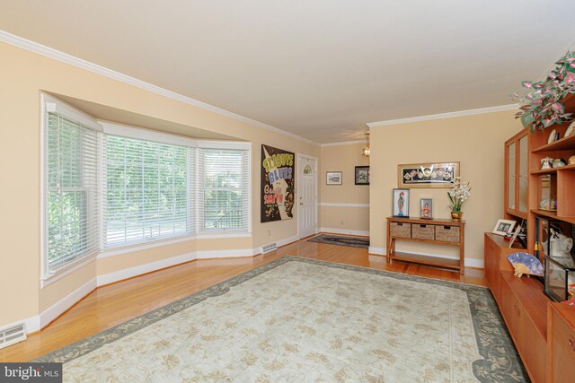 interior space with a wealth of natural light, hardwood / wood-style floors, and crown molding