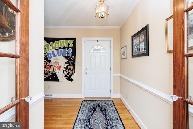 foyer featuring crown molding, a notable chandelier, and wood-type flooring