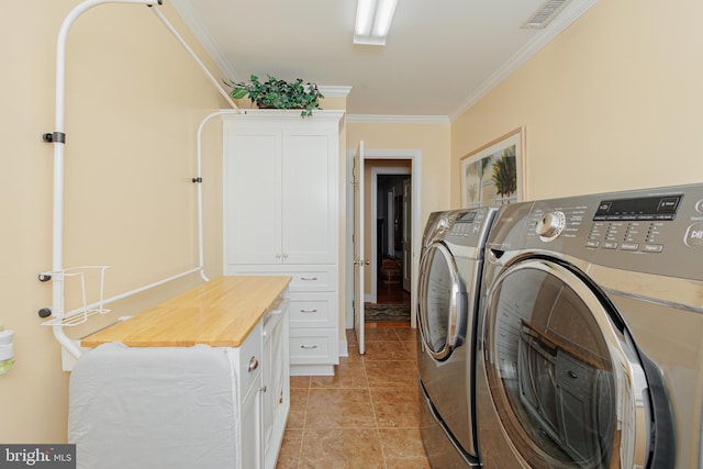 laundry room with cabinets, ornamental molding, light tile patterned flooring, and washing machine and clothes dryer