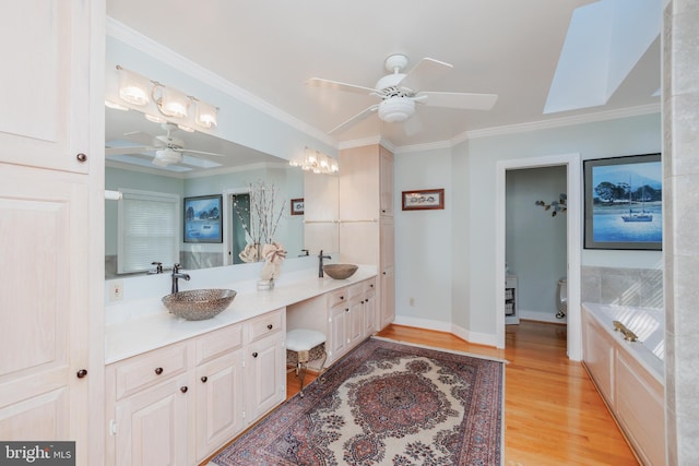 bathroom with vanity, ornamental molding, a tub, and wood-type flooring