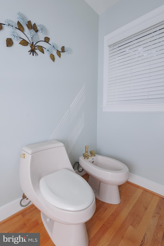 bathroom featuring toilet, hardwood / wood-style flooring, and a bidet