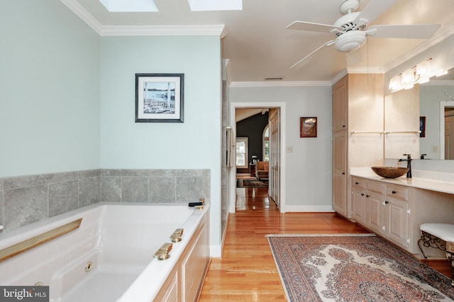 bathroom featuring wood-type flooring, ornamental molding, vanity, a bath, and ceiling fan