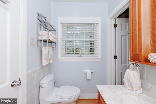 bathroom with tile walls, vanity, and toilet