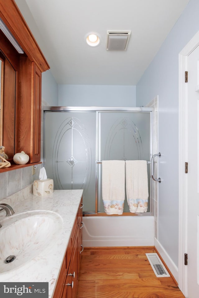 bathroom with vanity, bath / shower combo with glass door, and hardwood / wood-style floors