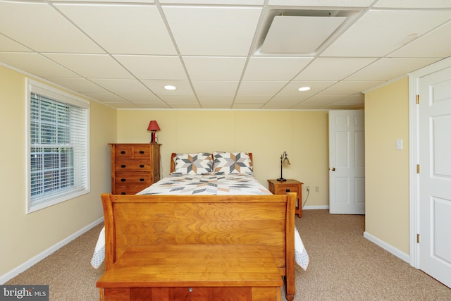 bedroom featuring a drop ceiling and light colored carpet