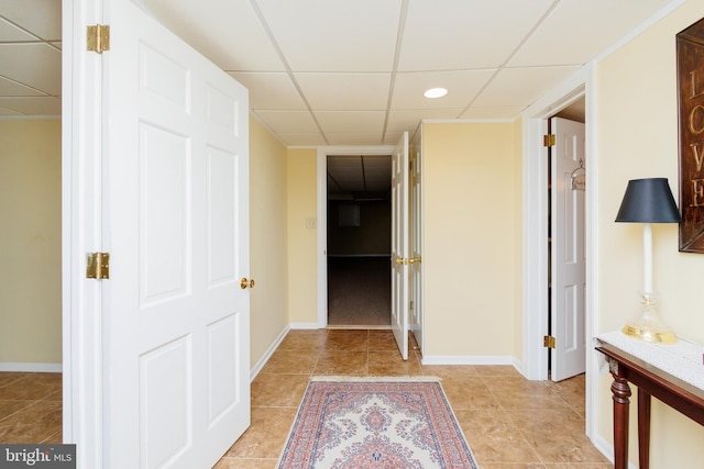 hallway with light tile patterned flooring and a paneled ceiling