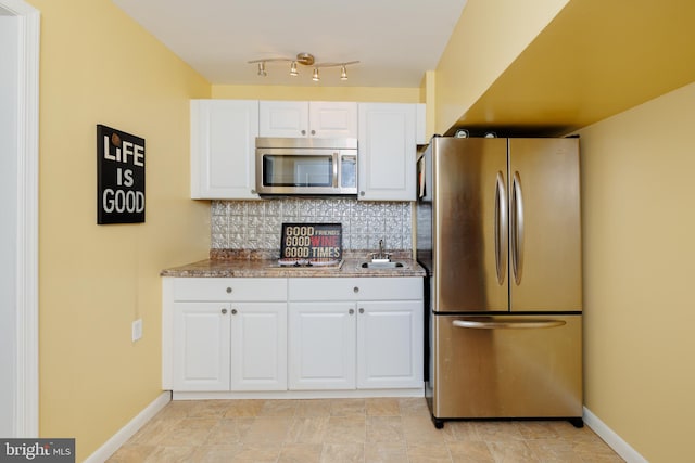 kitchen featuring tasteful backsplash, sink, white cabinetry, stainless steel appliances, and light stone counters