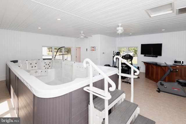 interior space featuring a hot tub, a healthy amount of sunlight, light tile patterned floors, and wooden walls