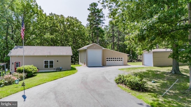 view of front of house with a front yard, an outbuilding, and a garage