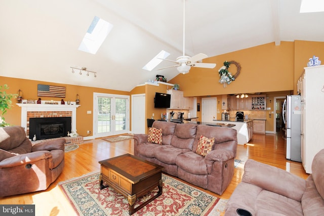 living room featuring light hardwood / wood-style flooring, french doors, high vaulted ceiling, and a brick fireplace