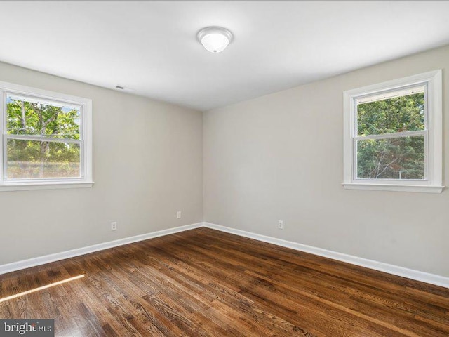 unfurnished room with a wealth of natural light and dark hardwood / wood-style flooring