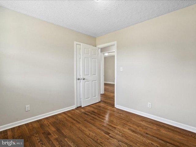 unfurnished room with dark hardwood / wood-style floors and a textured ceiling