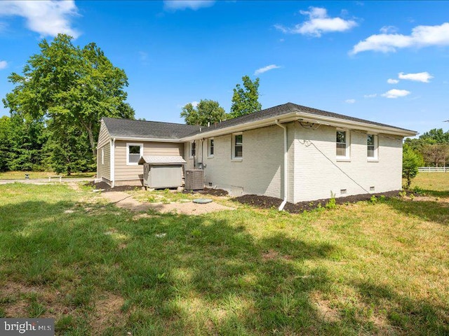 rear view of house featuring a hot tub, central AC, and a yard