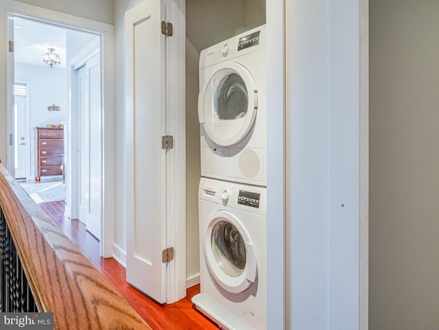 laundry room with hardwood / wood-style flooring and stacked washer / dryer