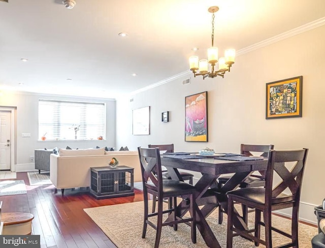 dining space with ornamental molding, an inviting chandelier, and dark hardwood / wood-style floors