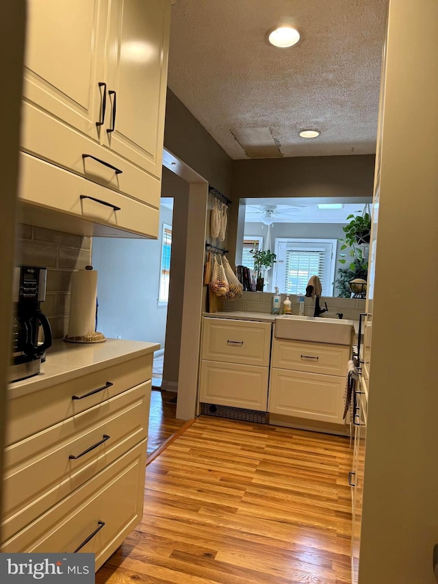 kitchen featuring sink, white cabinetry, a textured ceiling, light hardwood / wood-style floors, and ceiling fan