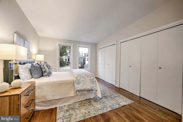 bedroom featuring lofted ceiling, dark hardwood / wood-style flooring, and two closets